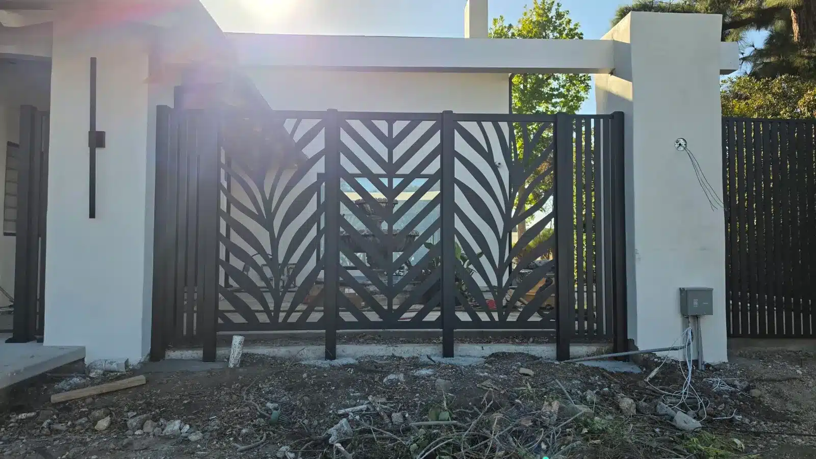 Black aluminum double gate with a decorative leaf pattern at a modern home