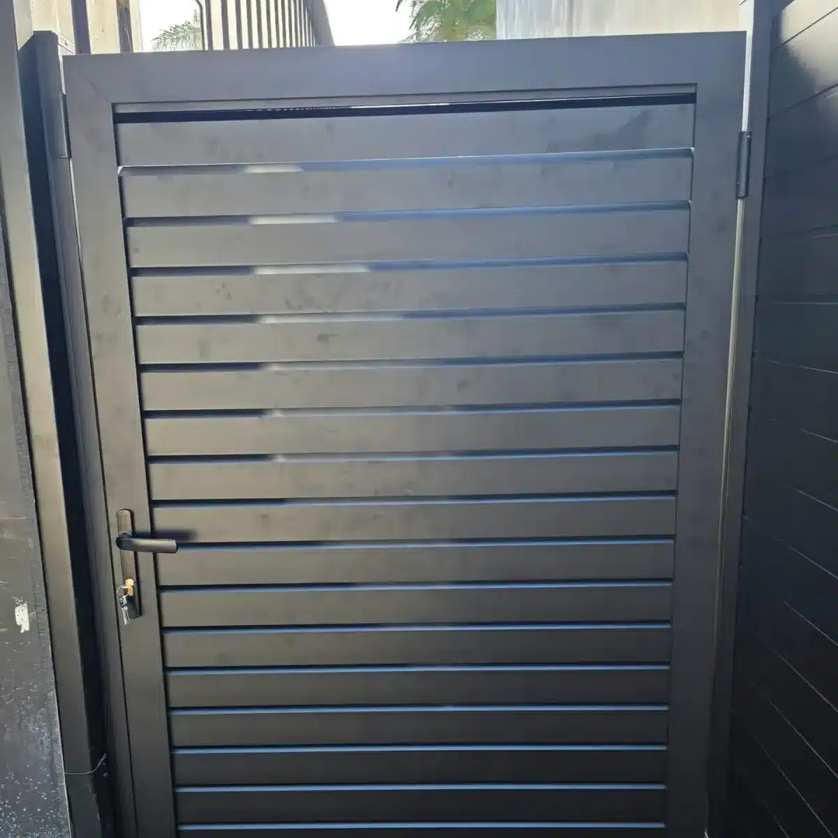 Close-up of a black powder-coated aluminum gate with horizontal slats