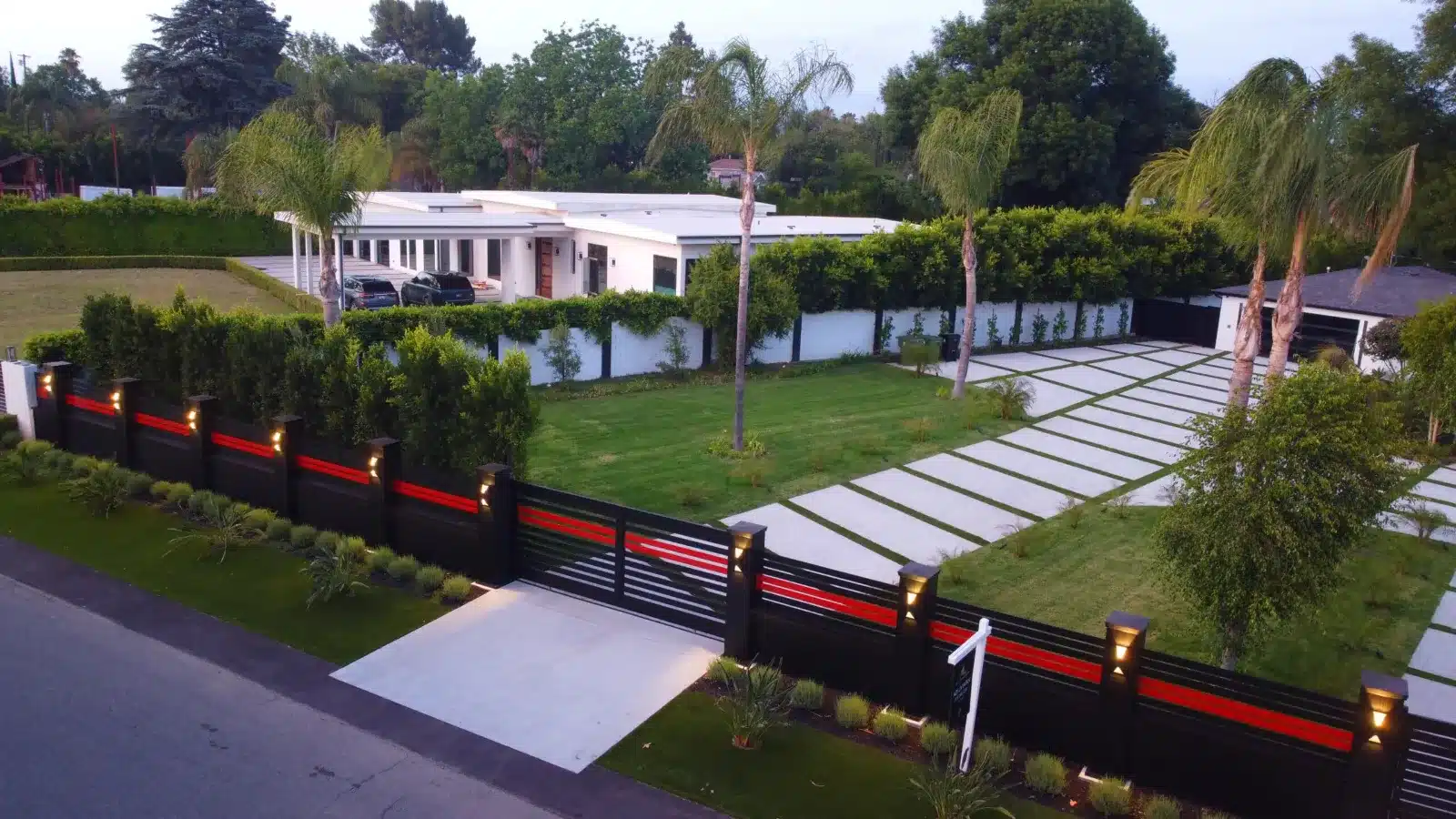 Black horizontal aluminum privacy fence with a matching driveway gate in front of a modern home